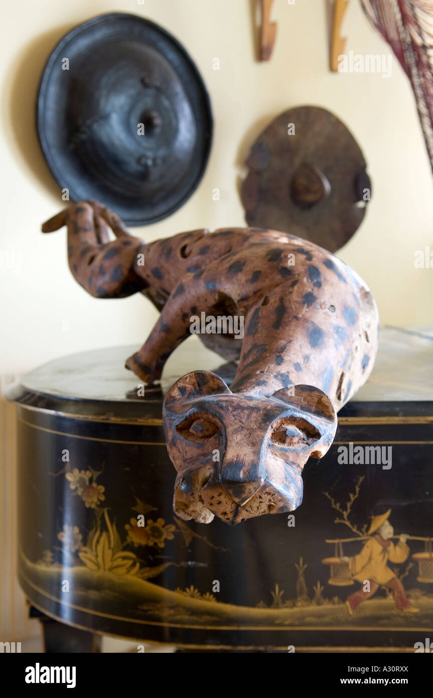 Wooden carved cheetah on top of grand piano with African shields in the background Stock Photo