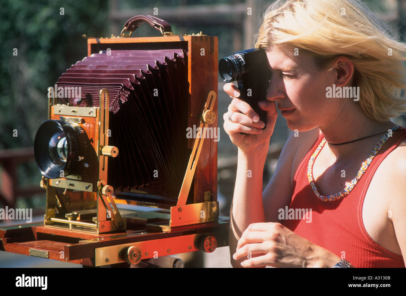 Female photographer standing next to a wooden field view camera Stock