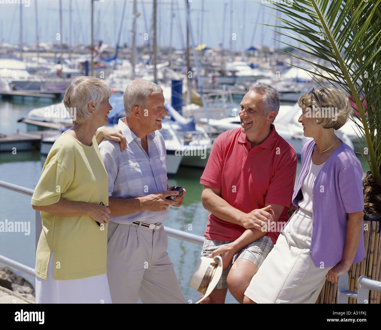 two retirement age couples chatting while on holiday, the marina at Vilamoura, Portugal, the Algarve Stock Photo