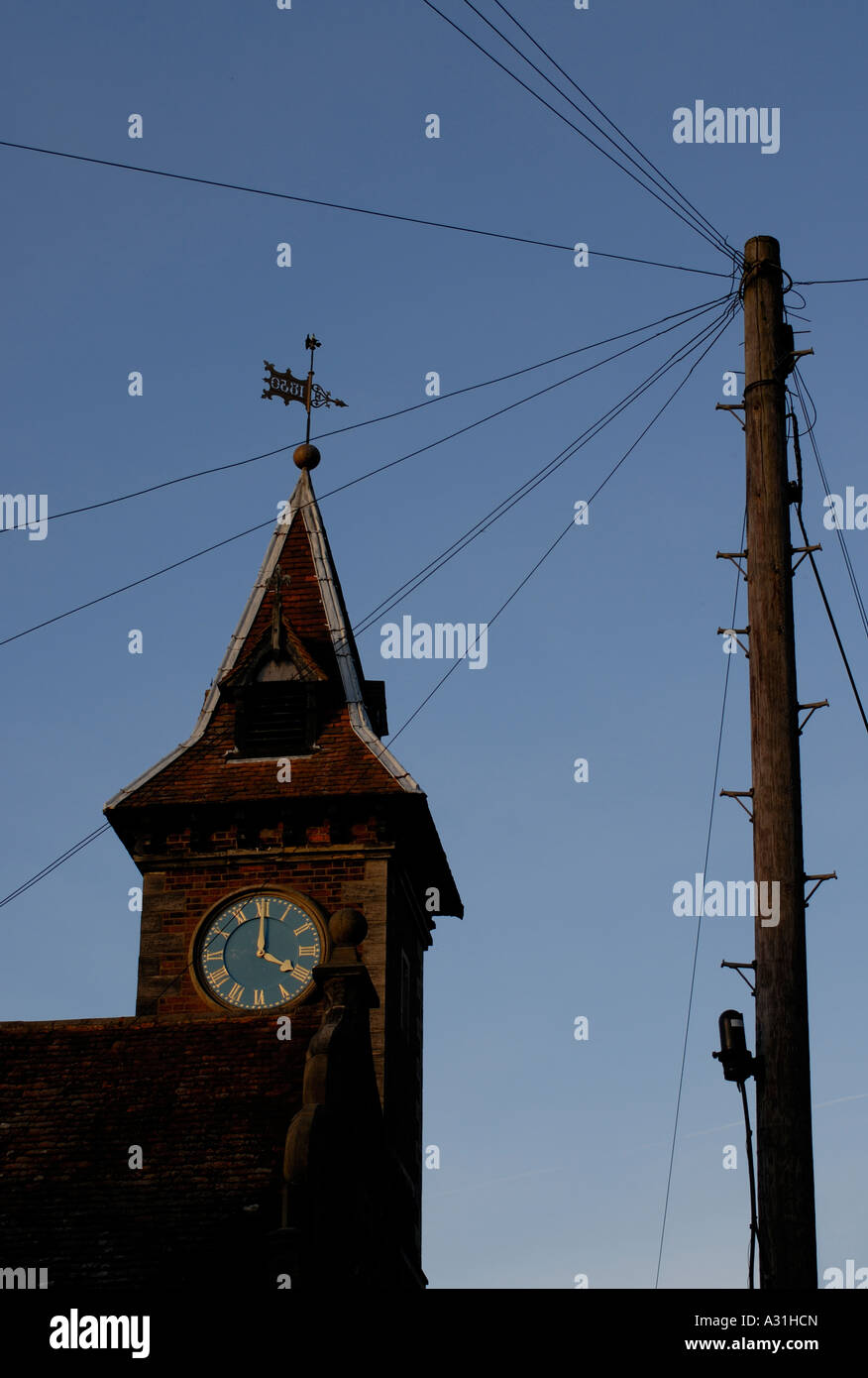 The clock tower of the old school and a telegraph pole The clock shows four o clock Stock Photo