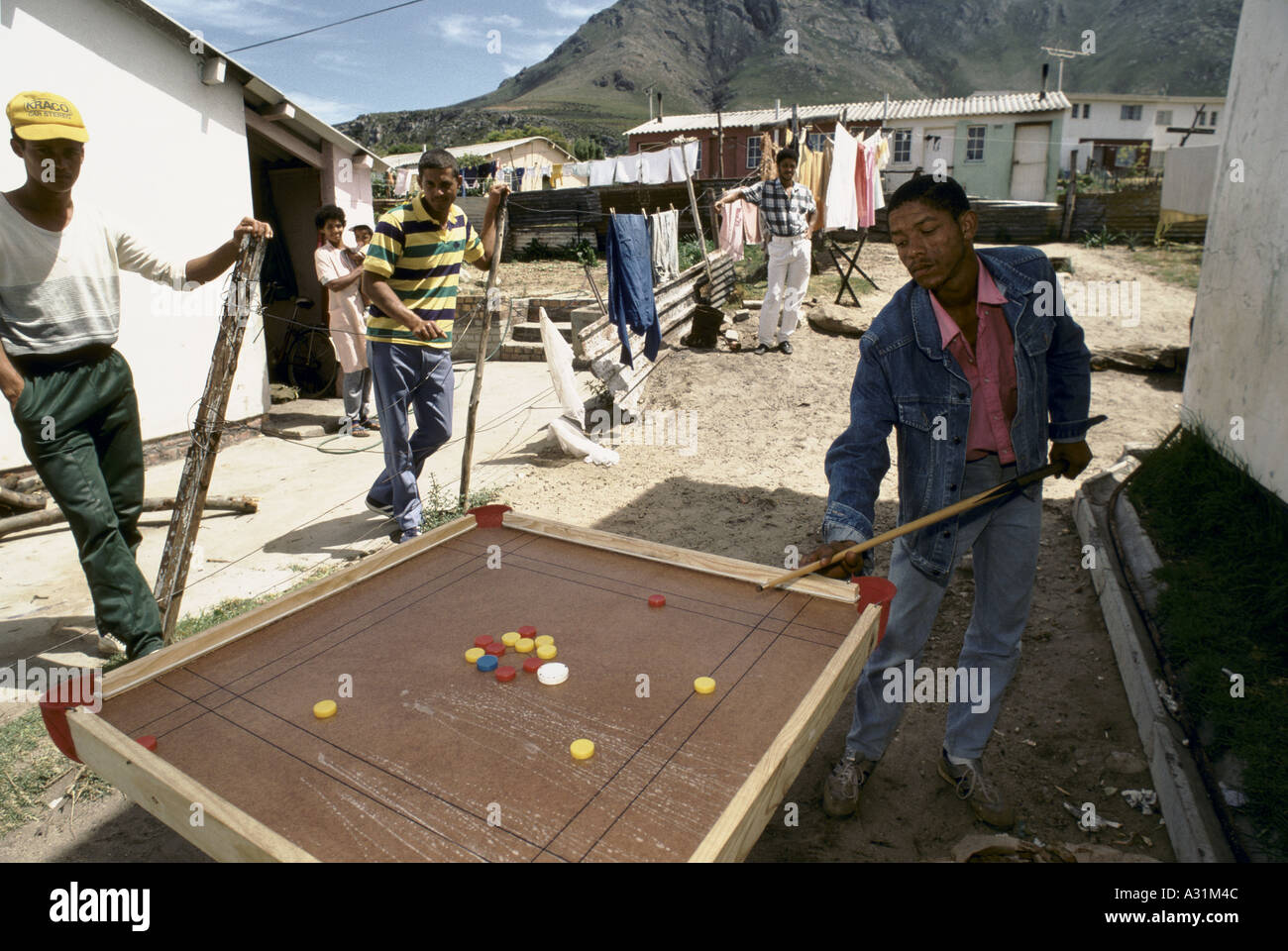 microcosm of apartheid kleinmond south africa a few black young men playing chess pool in a local neighbourhood outside huts 1988 Stock Photo
