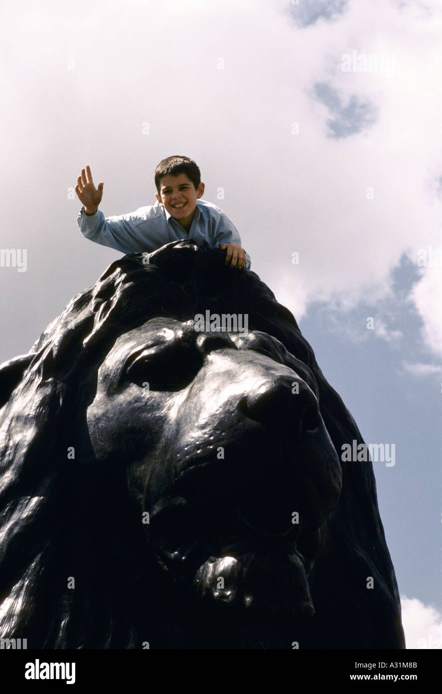 boy on top of lion statue in 'Trafalgar Square' Stock Photo