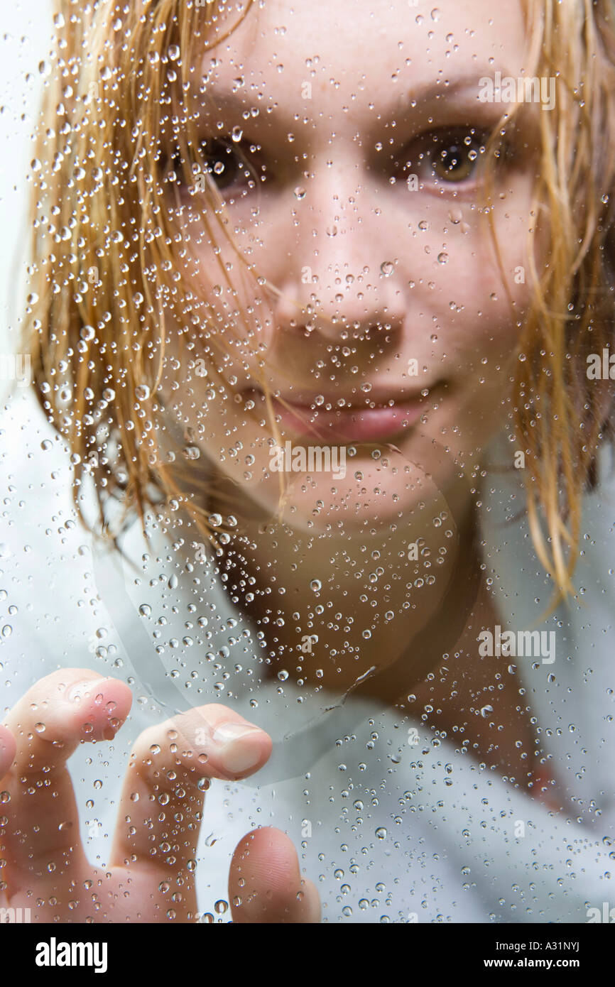 Woman looking anxious through glass of shower Stock Photo