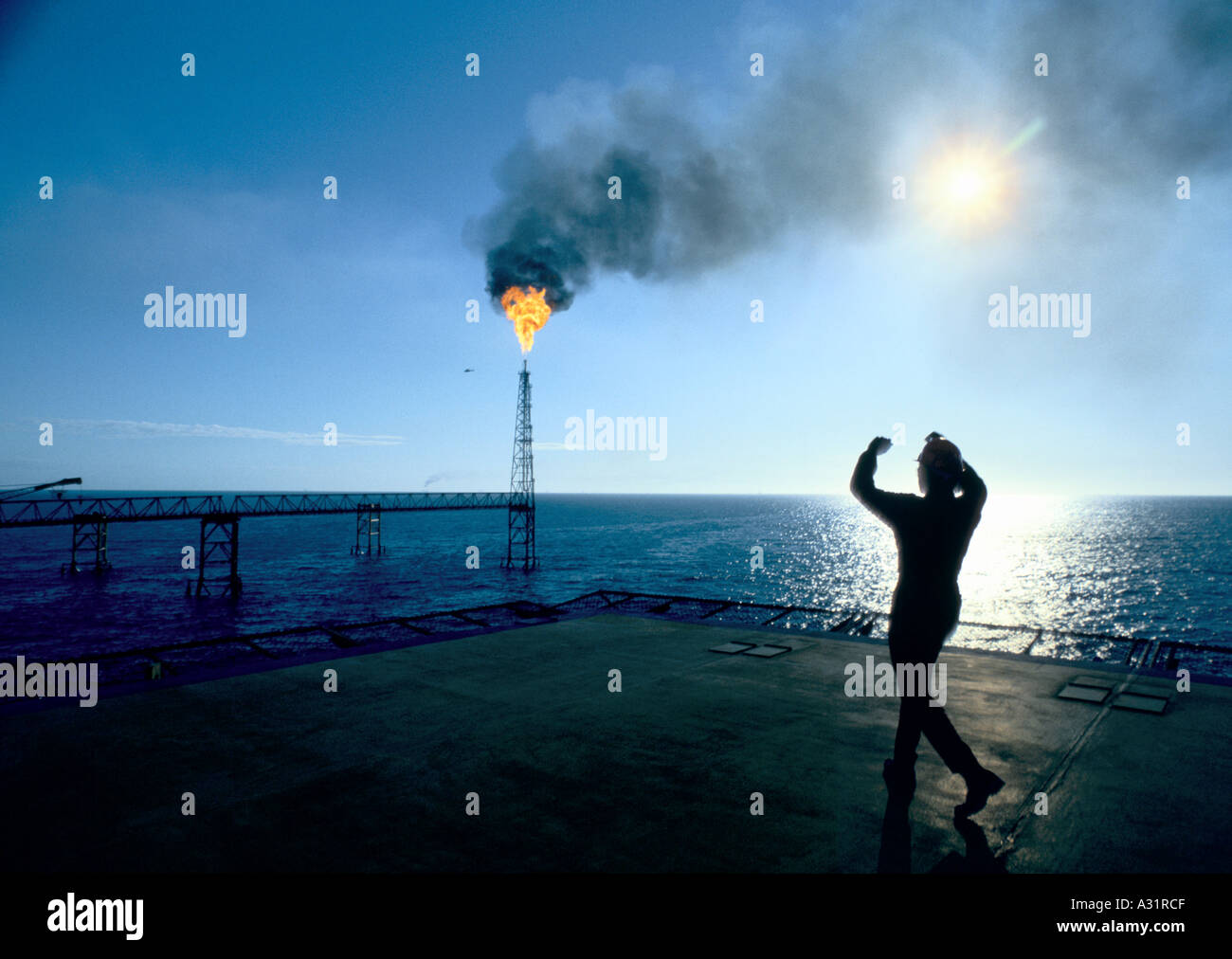 man watching the flame of an oil rig Stock Photo