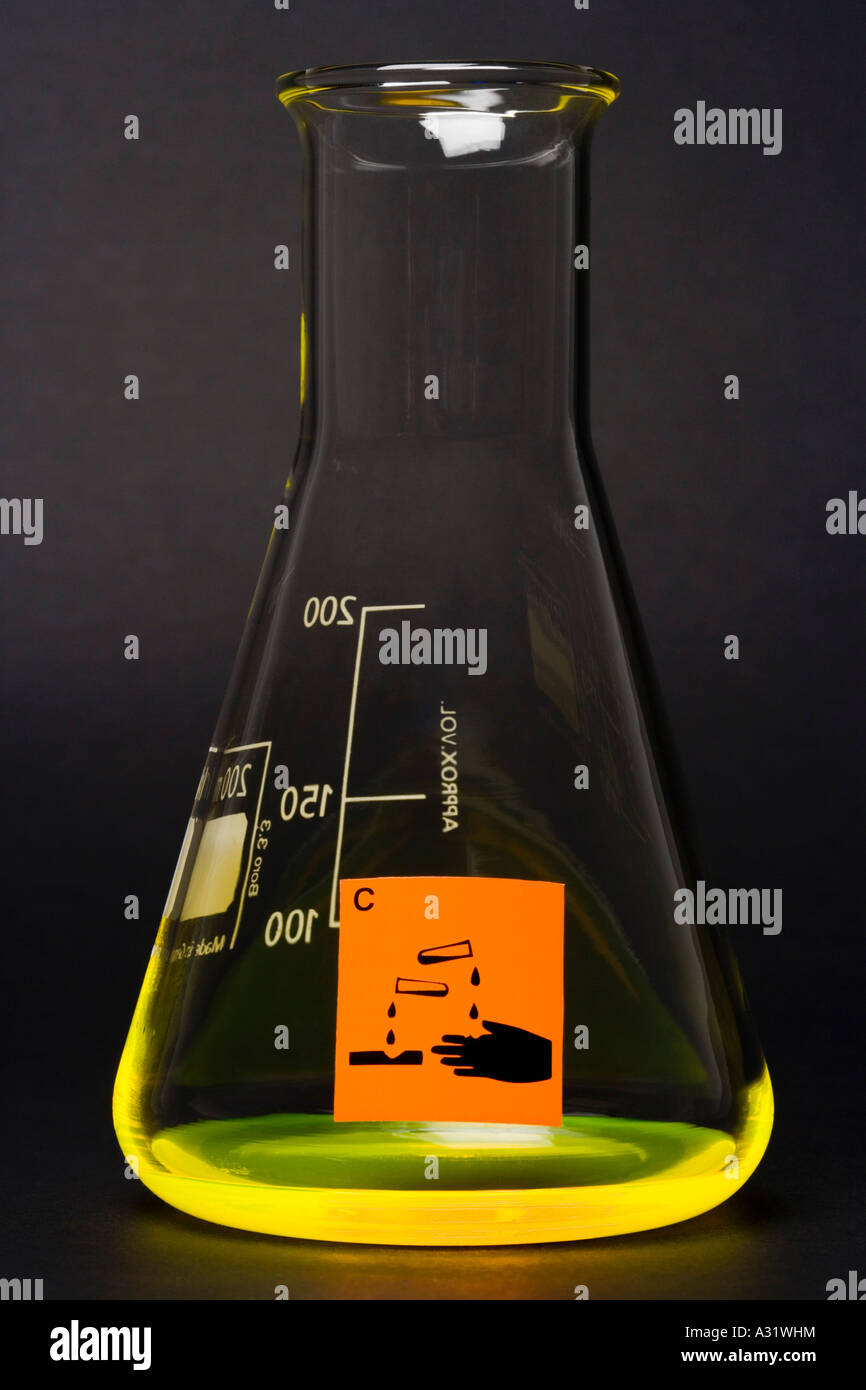 Corrosive label on conical flask containing yellow liquid Stock Photo