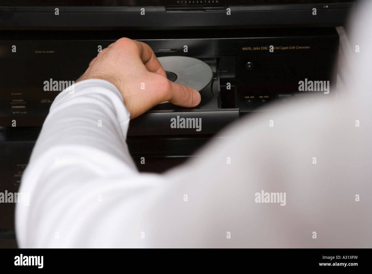 Man inserting disk into DVD player Stock Photo