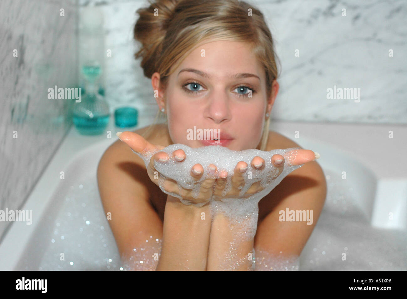 Woman taking bubble bath blowing on foam Stock Photo