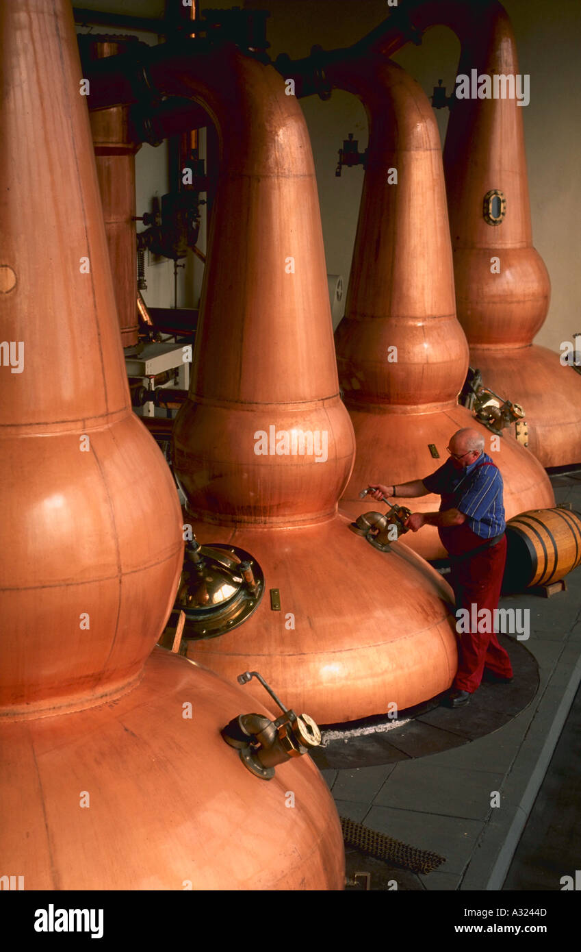 Copper whiskey stills and stillman at distillery in Scotland Stock Photo