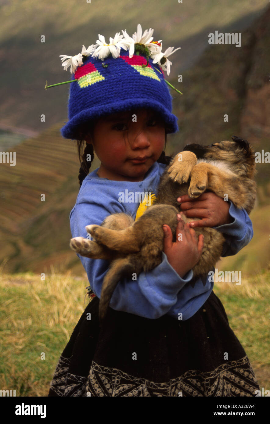Vertical portrait of a pretty little Peruvian girl holding a puppy in her arms, Peru, South America Stock Photo