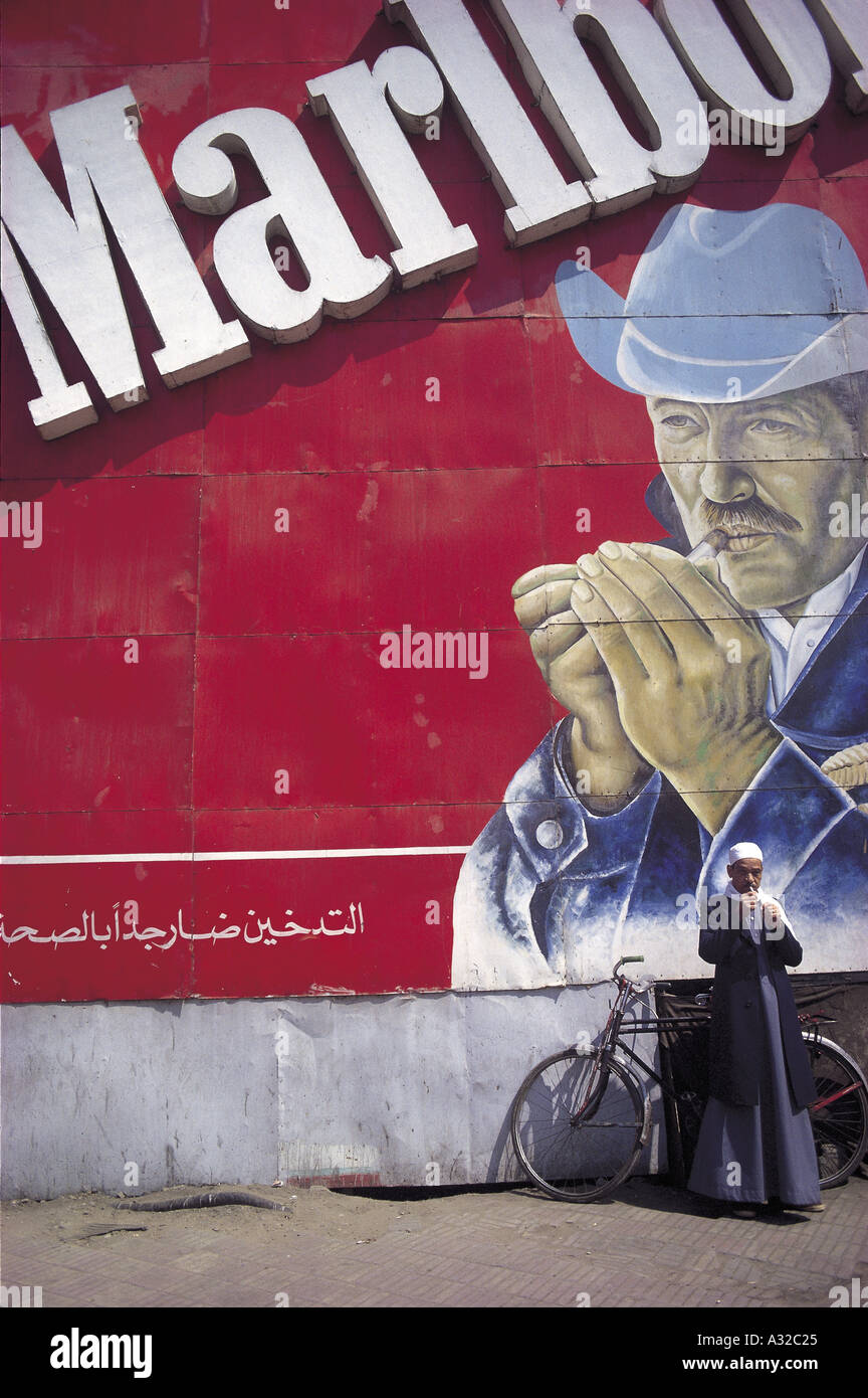 Man smoking a cigarette beneath a large sign advertising Marlboro in Cairo, Egypt Stock Photo