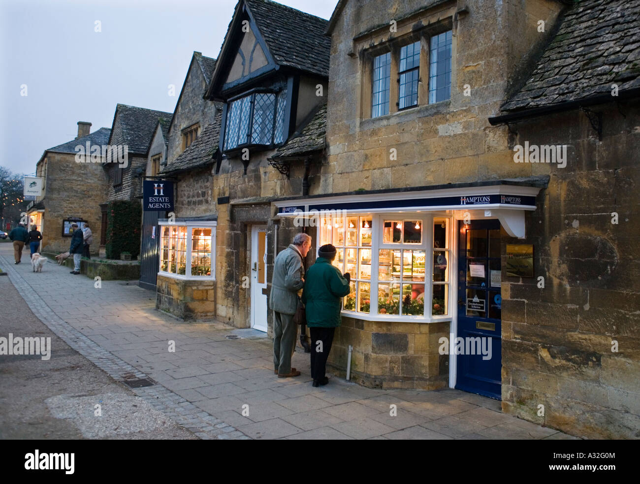 A couple looking in the window of an estate agent in Broadway Worcestershire Stock Photo