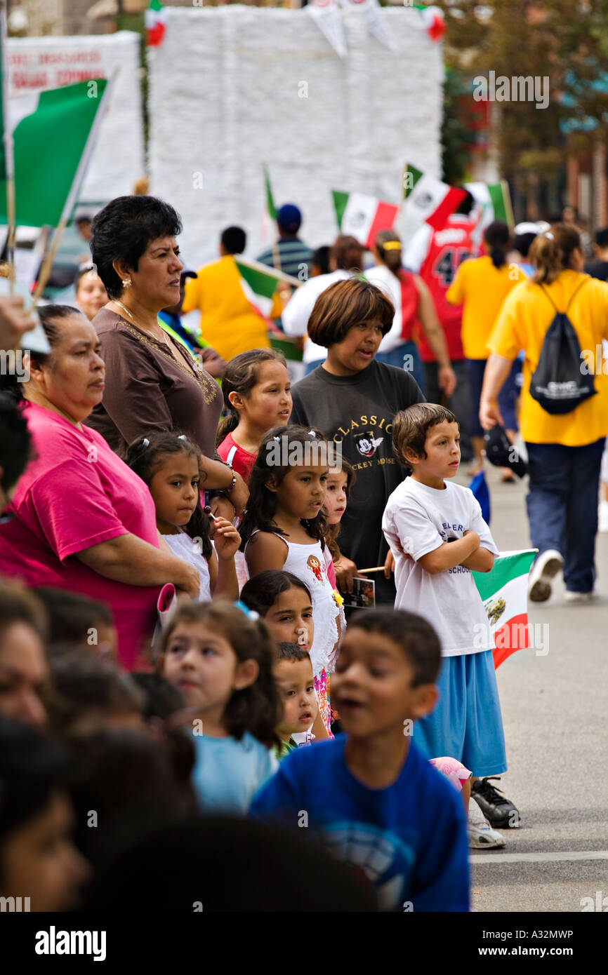 ILLINOIS Chicago Hispanic boys and girls and adult women stand along street and watch Mexican Independence Day Parade on 18th St Stock Photo