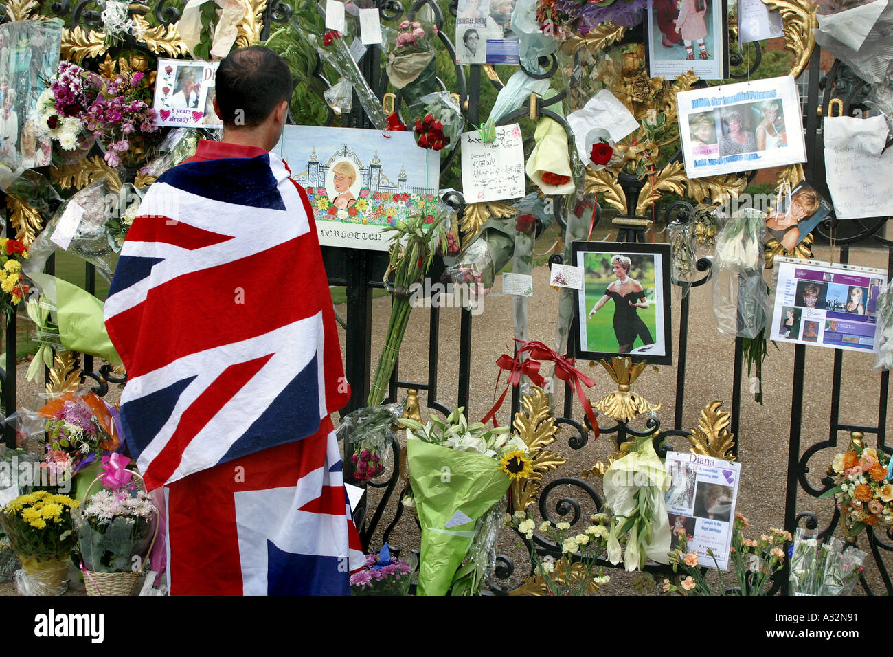 mourner wrapped in union jack looks at the messages hanging on kensington palace gates in memory of princess diana Stock Photo