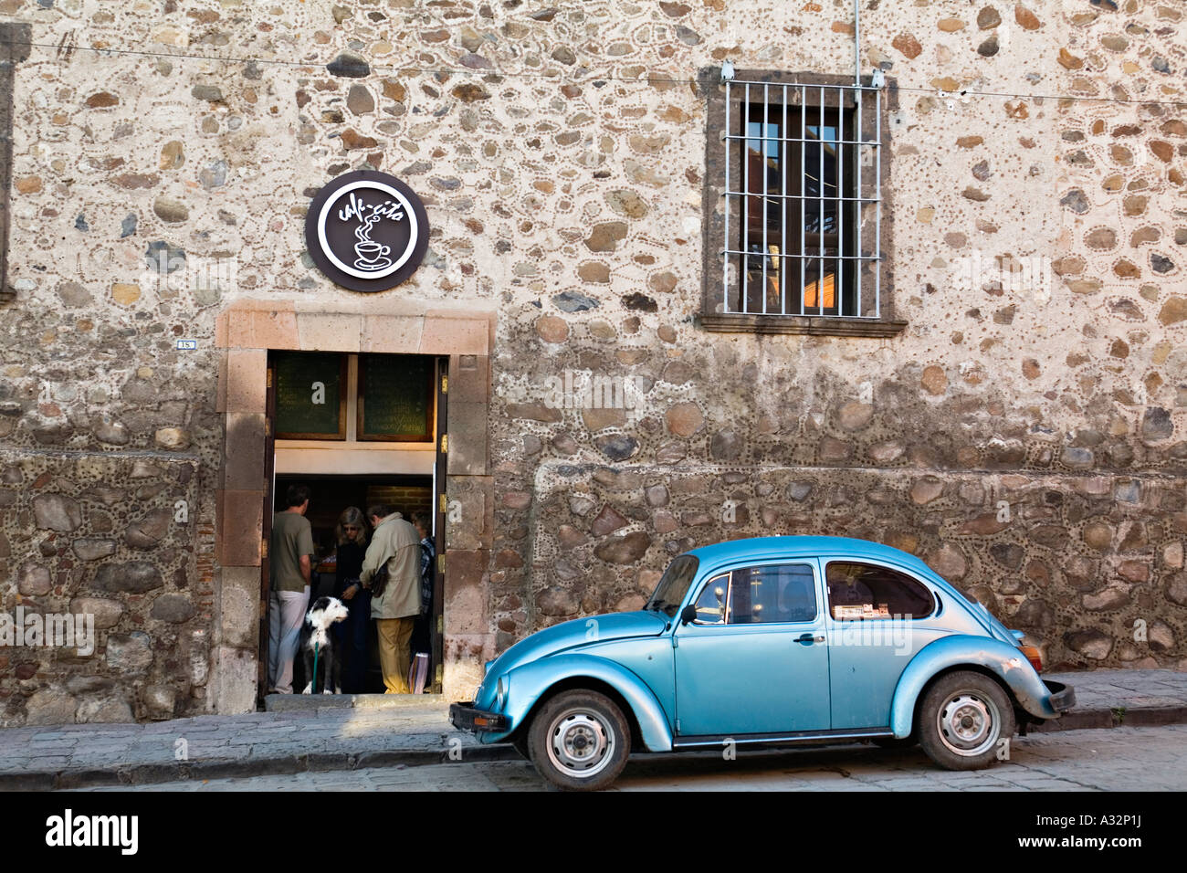 MEXICO San Miguel de Allende Blue Volkswagen beetle car parked on street coffee shop people and dog stand in doorway to store Stock Photo