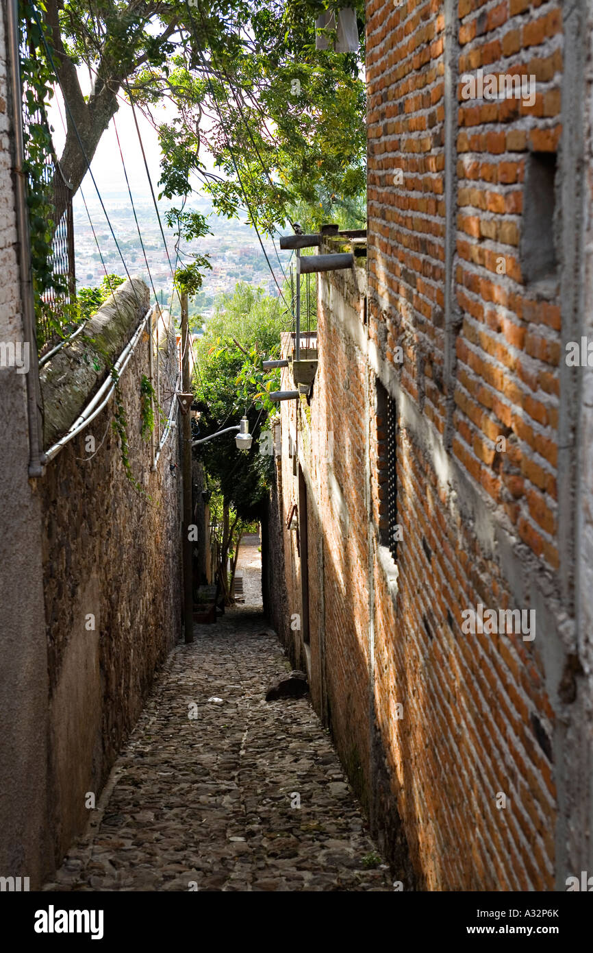 MEXICO San Miguel de Allende Narrow sidewalk between a stone wall and brick building on steep hill above town Stock Photo
