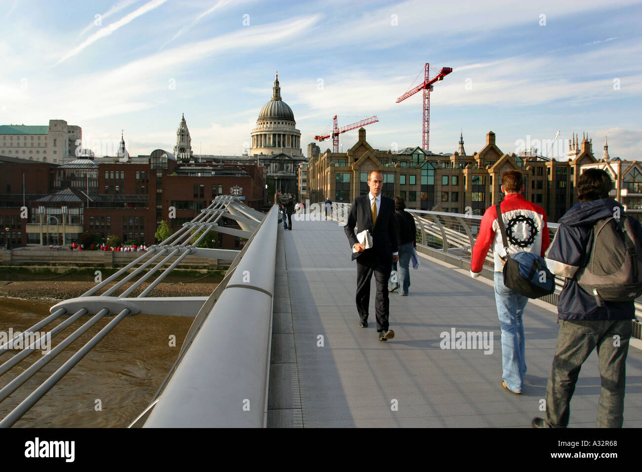 pedestrians crossing the millennium bridge with a view of St Pauls cathedral behind Stock Photo