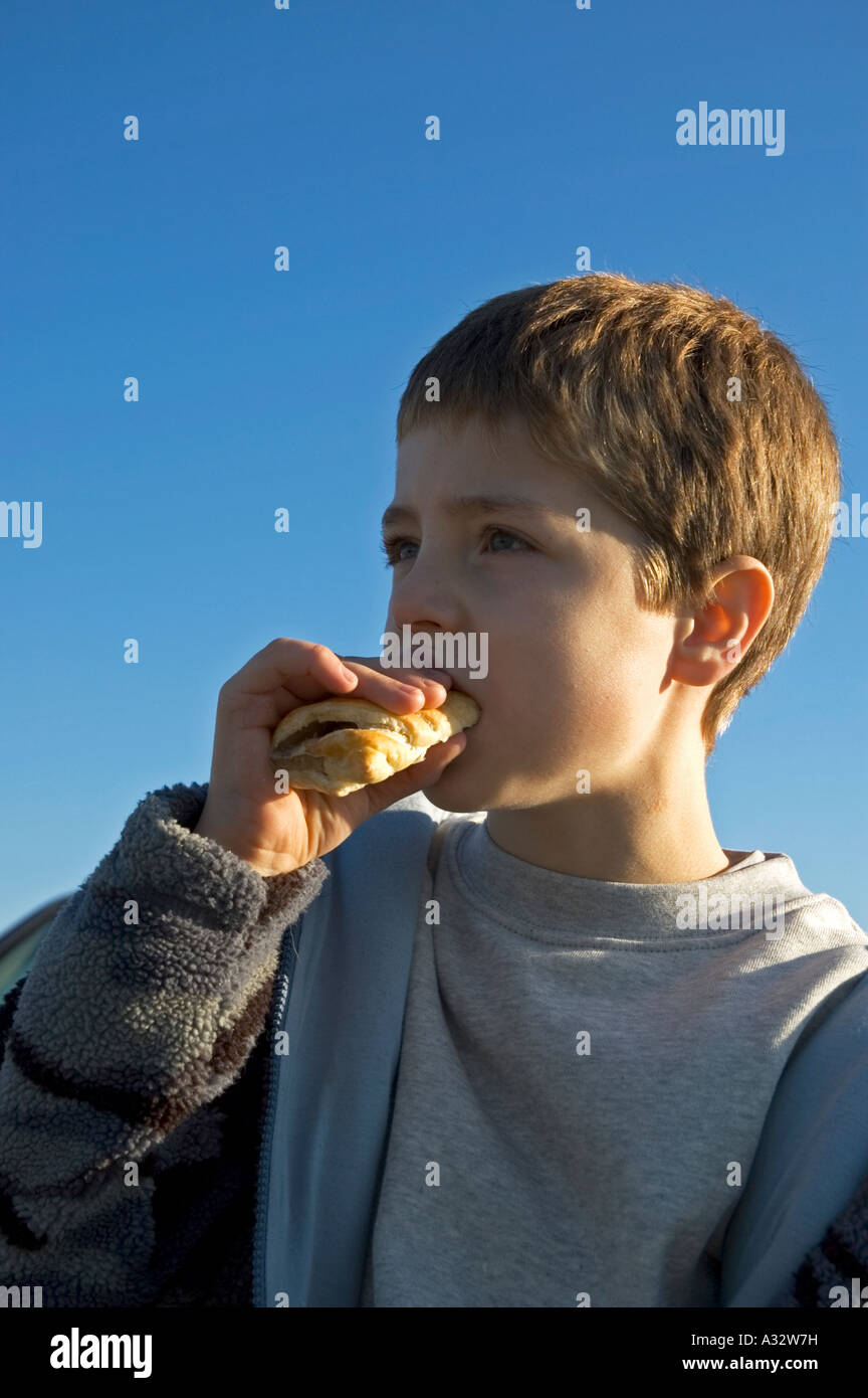 a young boy eating a sausage roll Stock Photo