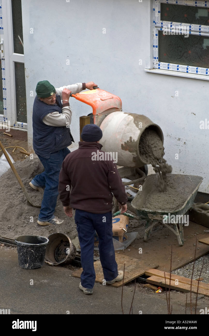 two builders using a cement mixer on a development of new homes in cornwall,england Stock Photo