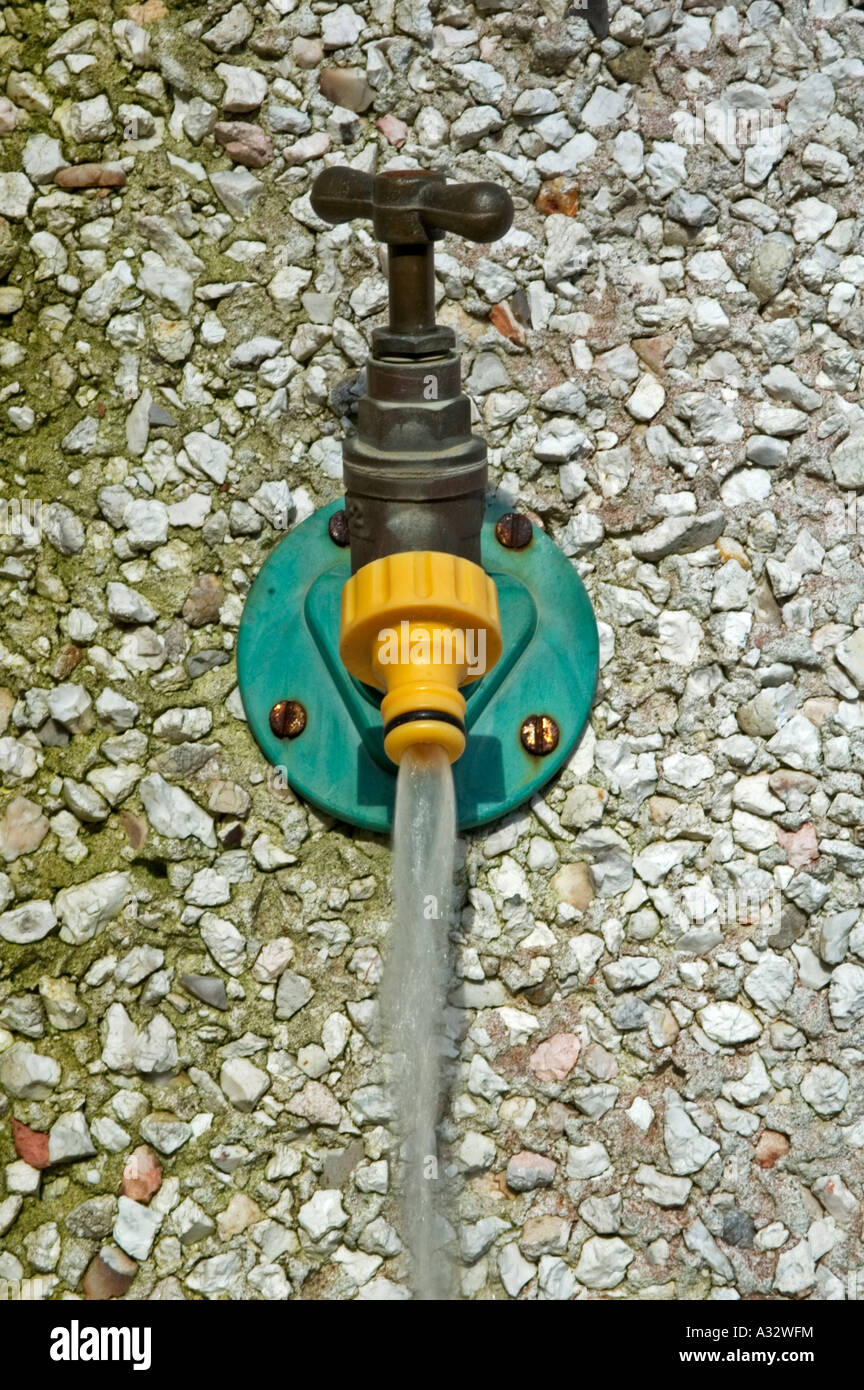 an outdoor water tap left running, wasting water Stock Photo