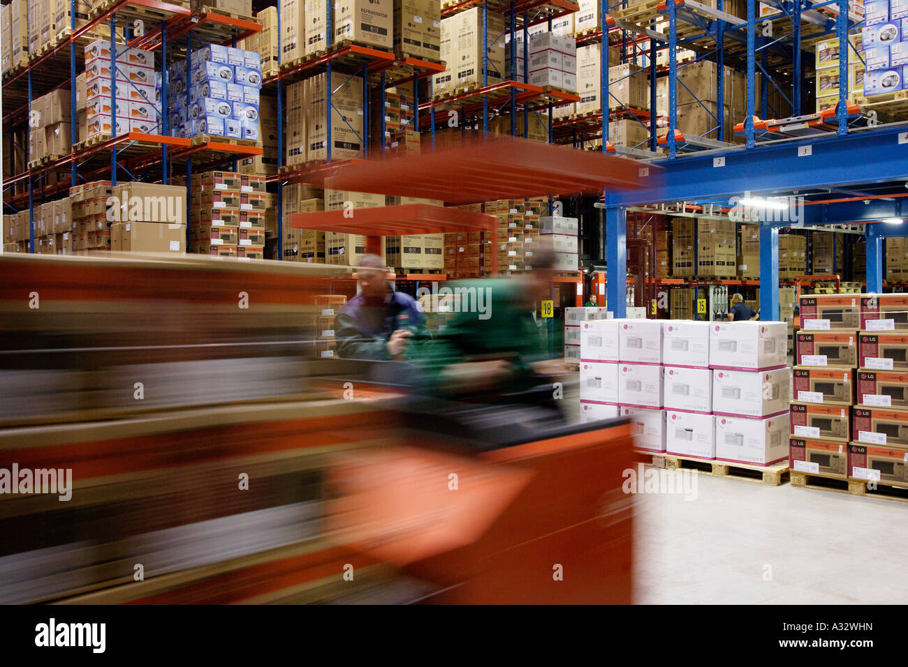 Warehousemen operating forklifts in a high rack warehouse, Willich, Germany Stock Photo