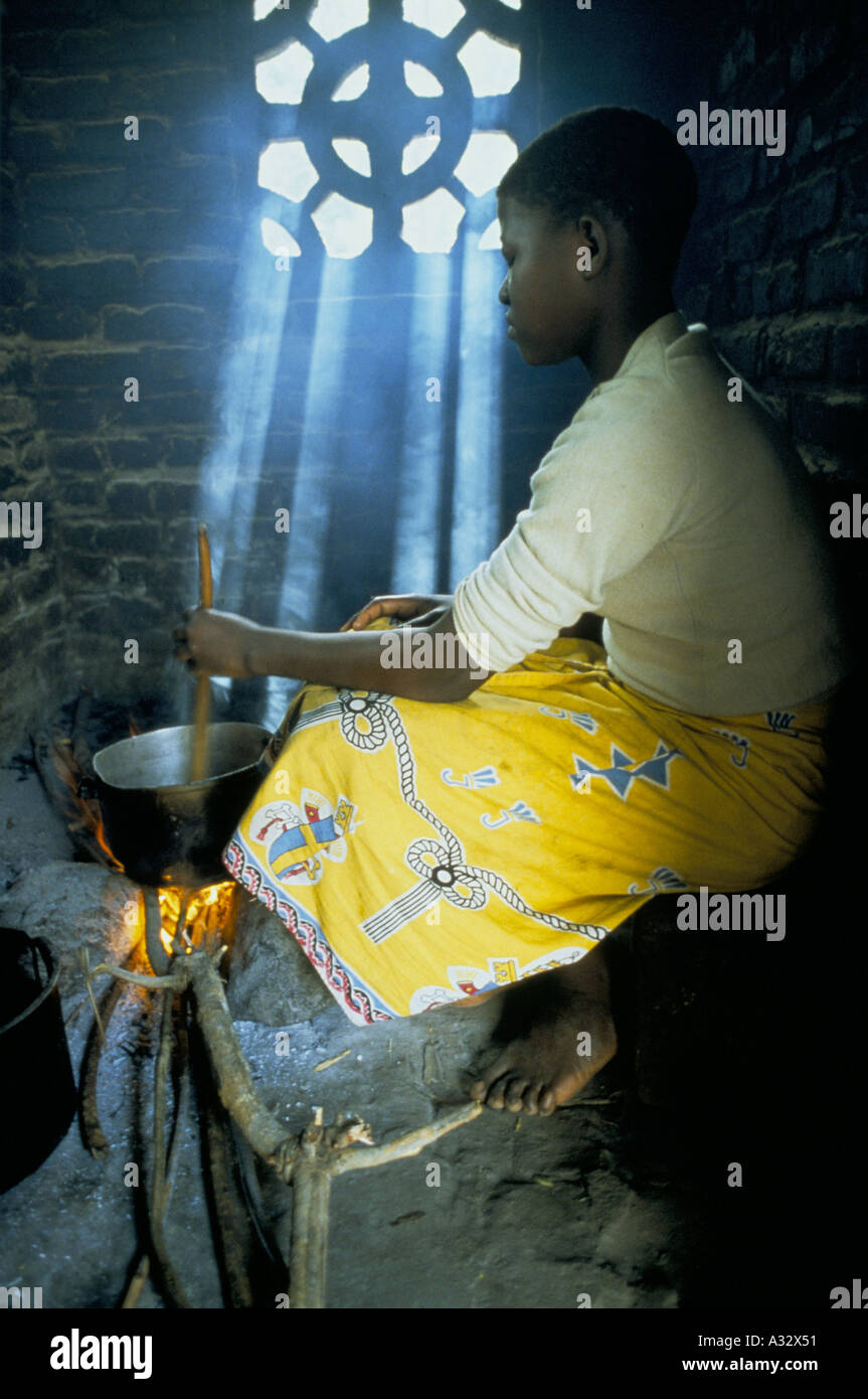 Woman cooking maze in a kitchen filled with shafts of light, Malawi
