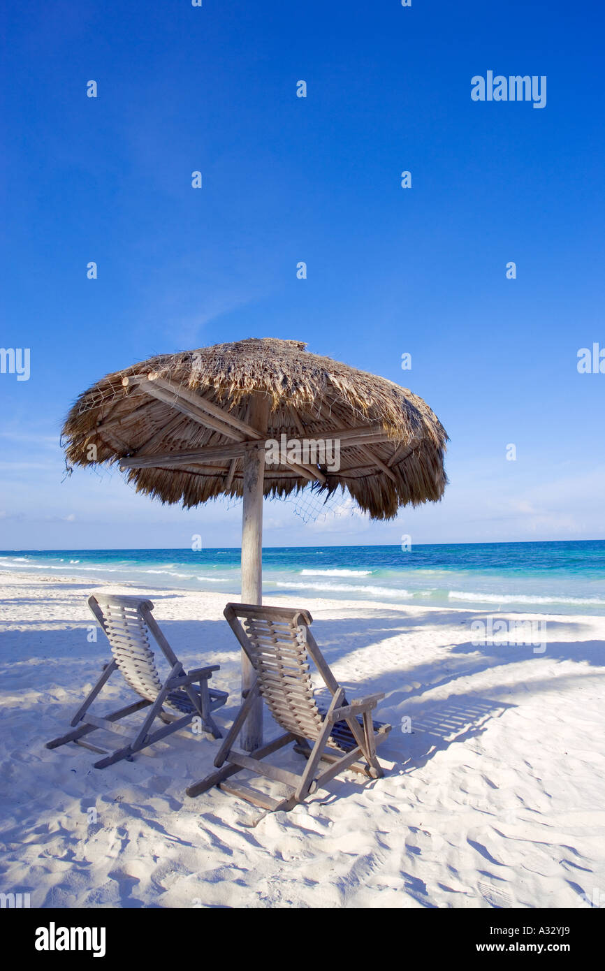 Caribbean beach scene with two chairs under shade palapa near Cancun, Mexico. Stock Photo
