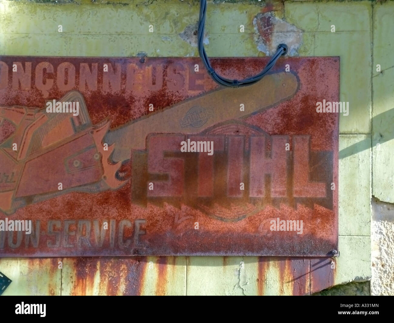 old rusty advertising sign of the company Stihl for motor saw on a old weather beaten wall Stock Photo
