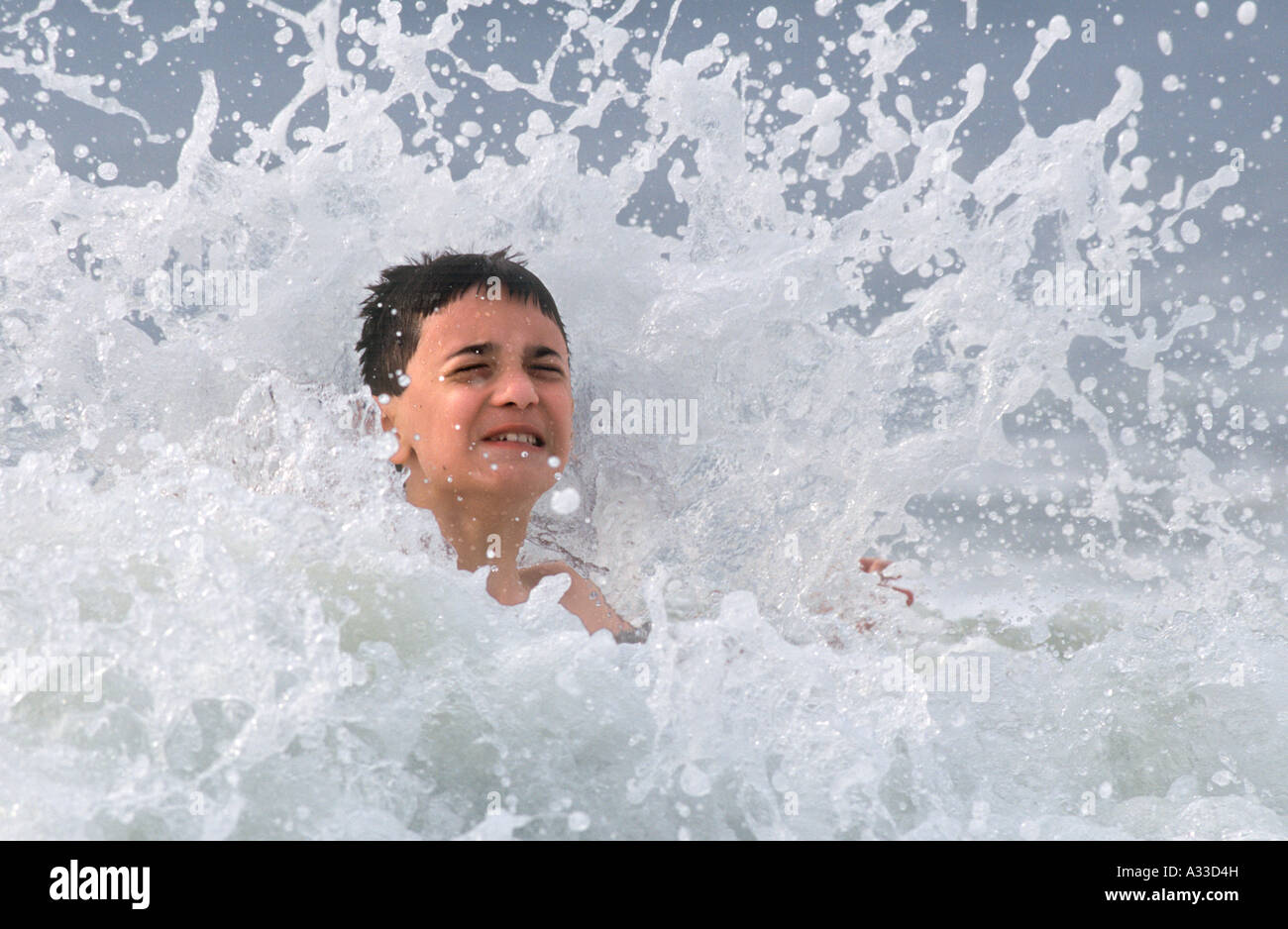 A young boy splashing and playing in the waves of the ocean Stock Photo ...