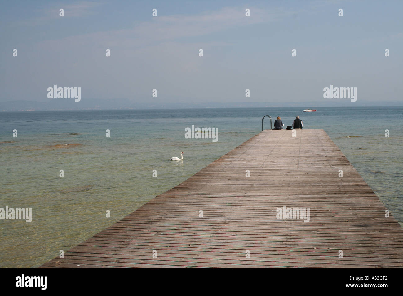 Contemplating the beautiful clear water of  Lake Garda from a pier on the Sirmione peninsula Veneto, Italy. Stock Photo