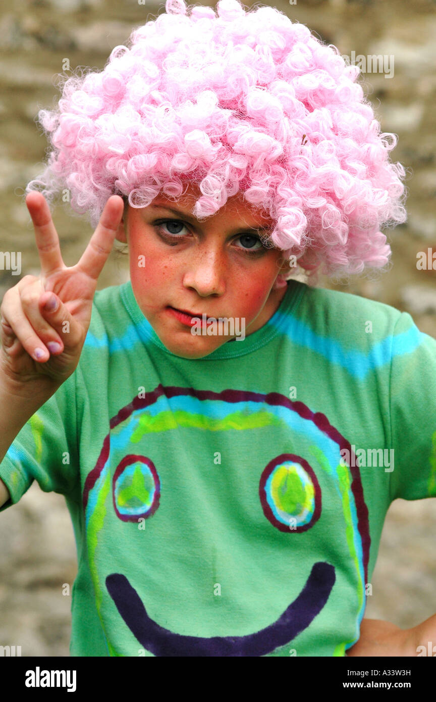 Portrait of young girl dressed up as a hippy giving the peace sign and wearing a smily face t-shirt Stock Photo