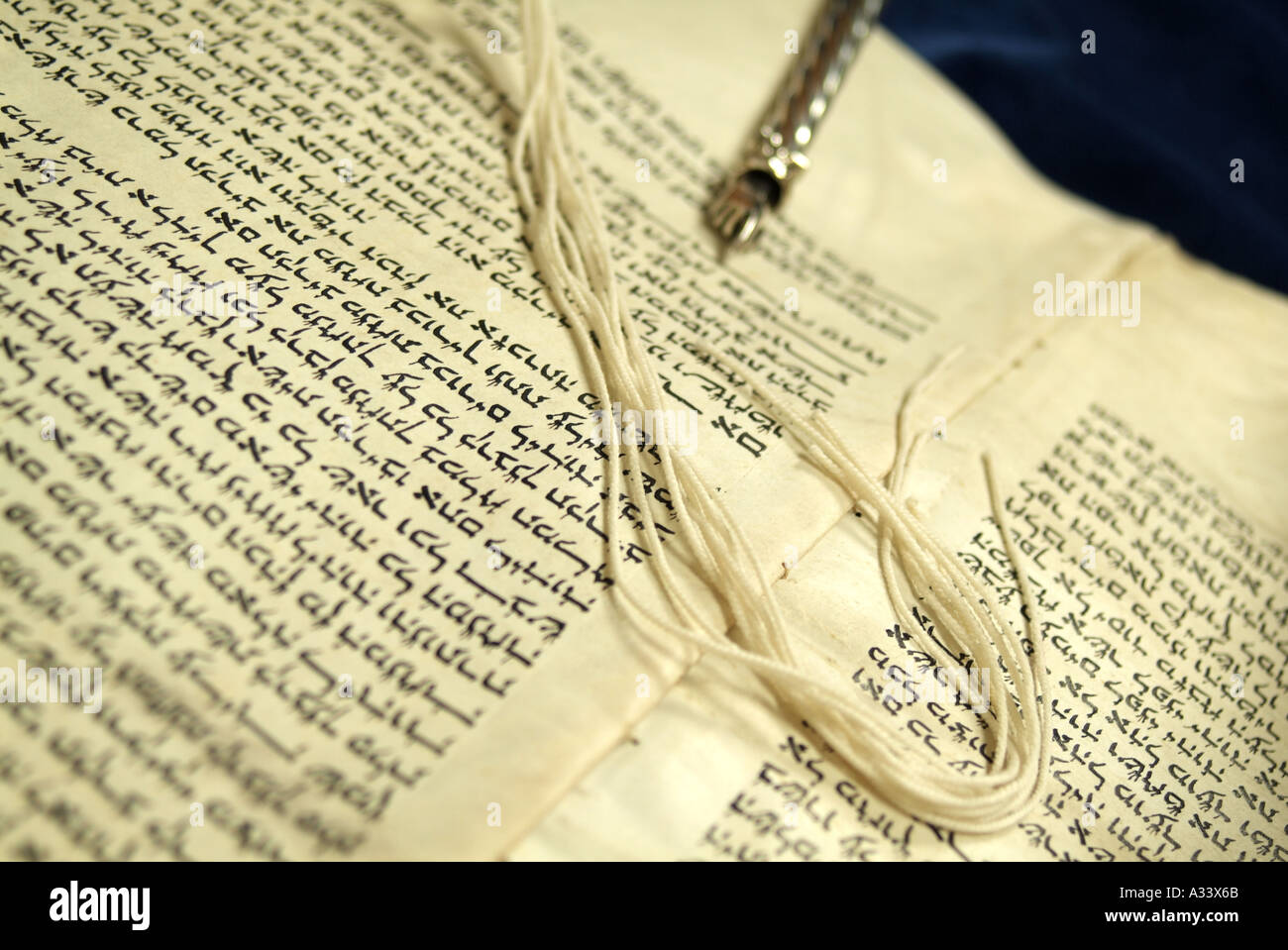 Torah scroll with silver yad pointer and fridges of prayer shawl on Hebrew script words Stock Photo