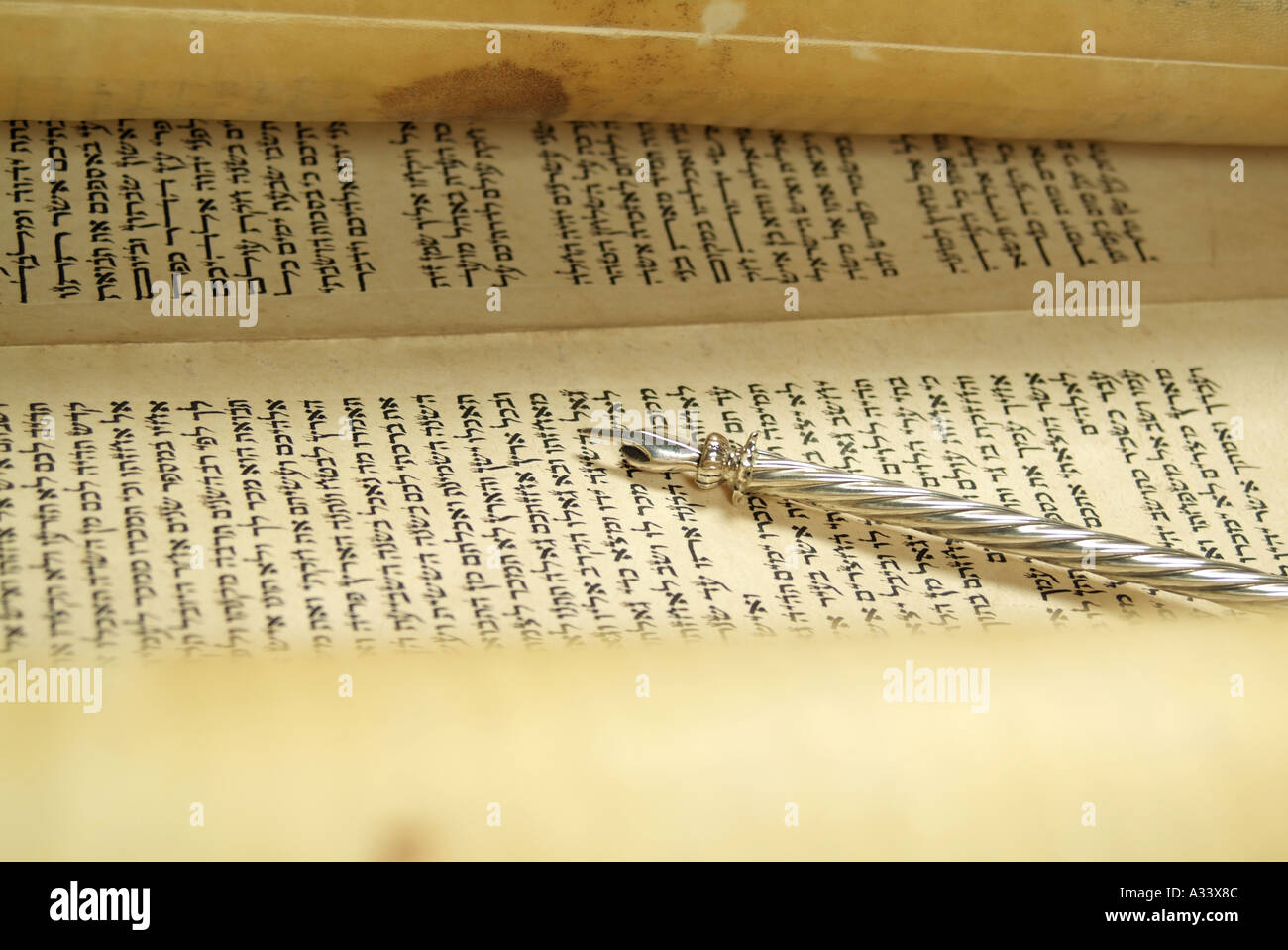 Hebrew Torah Scroll with yad pointer resting on Hebrew letters Stock Photo