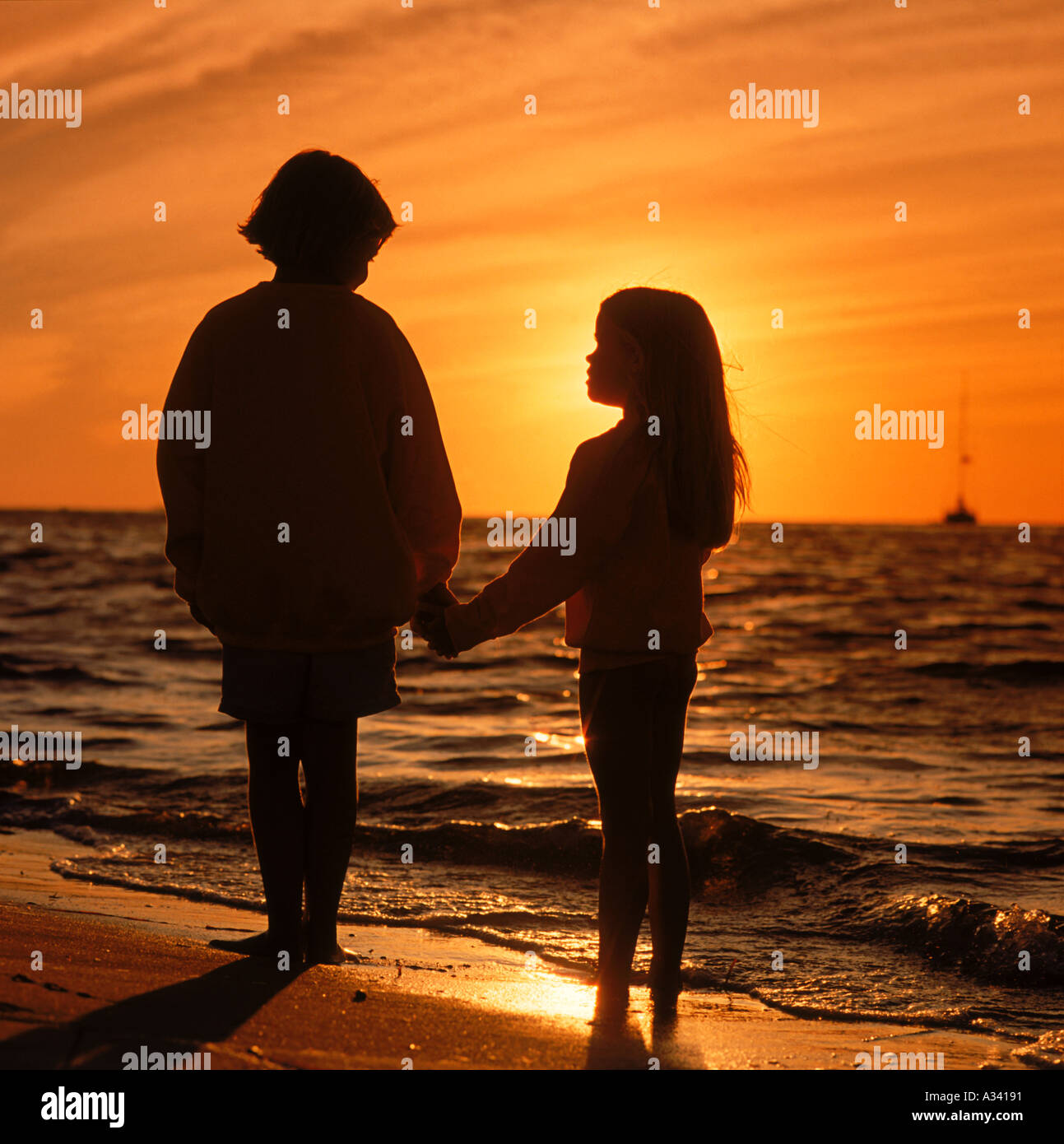 Silhouette Of A Young Boy And Girl Holding Hands On The Shore As The Sun Sets Into The Ocean In Front Of Them Stock Photo Alamy Silhouette Of A Young Boy And Girl Holding Hands On The Shore As The Sun Sets Into The Ocean In Front Of Them Stock Photo Alamy