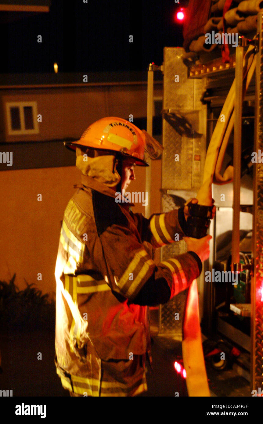 Firefighter from the Occidental Volunteer Fire Department connects hoses during a nightime training exercise at Harmony School Occidental California USA blurry action image Stock Photo