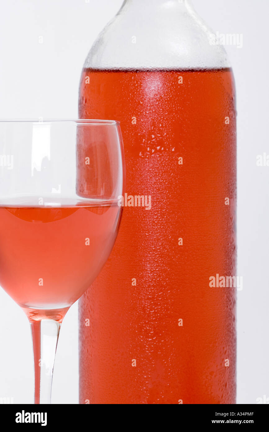 Glass of chilled red or rose wine next to bottle with white isolated