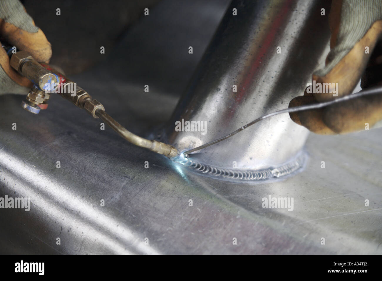Skilled lead worker burns or welds a joint on a lead pipe collar Stock Photo