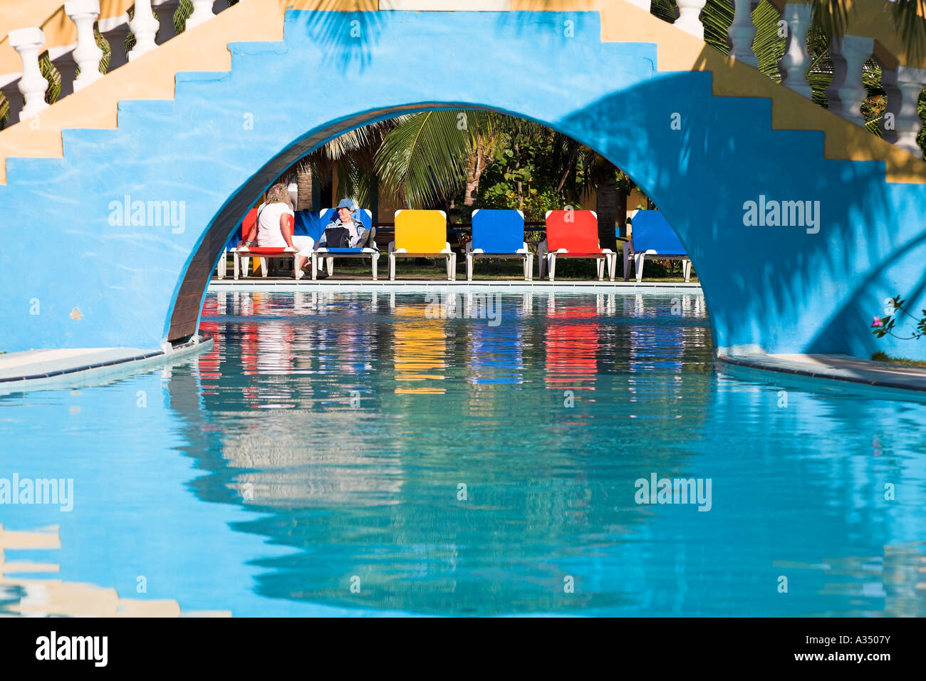 Tourists relaxing and sunbathing on sun beds beside a pool, Trinidad, Sancti Spiritus Province, Cuba Stock Photo