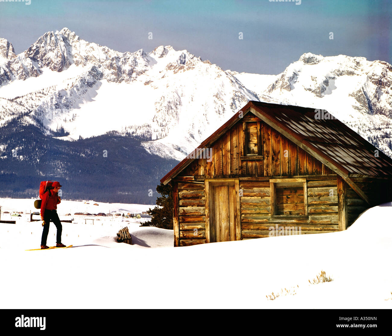 Outdoorsman on snowshoes and carrying a backpack approaches remote