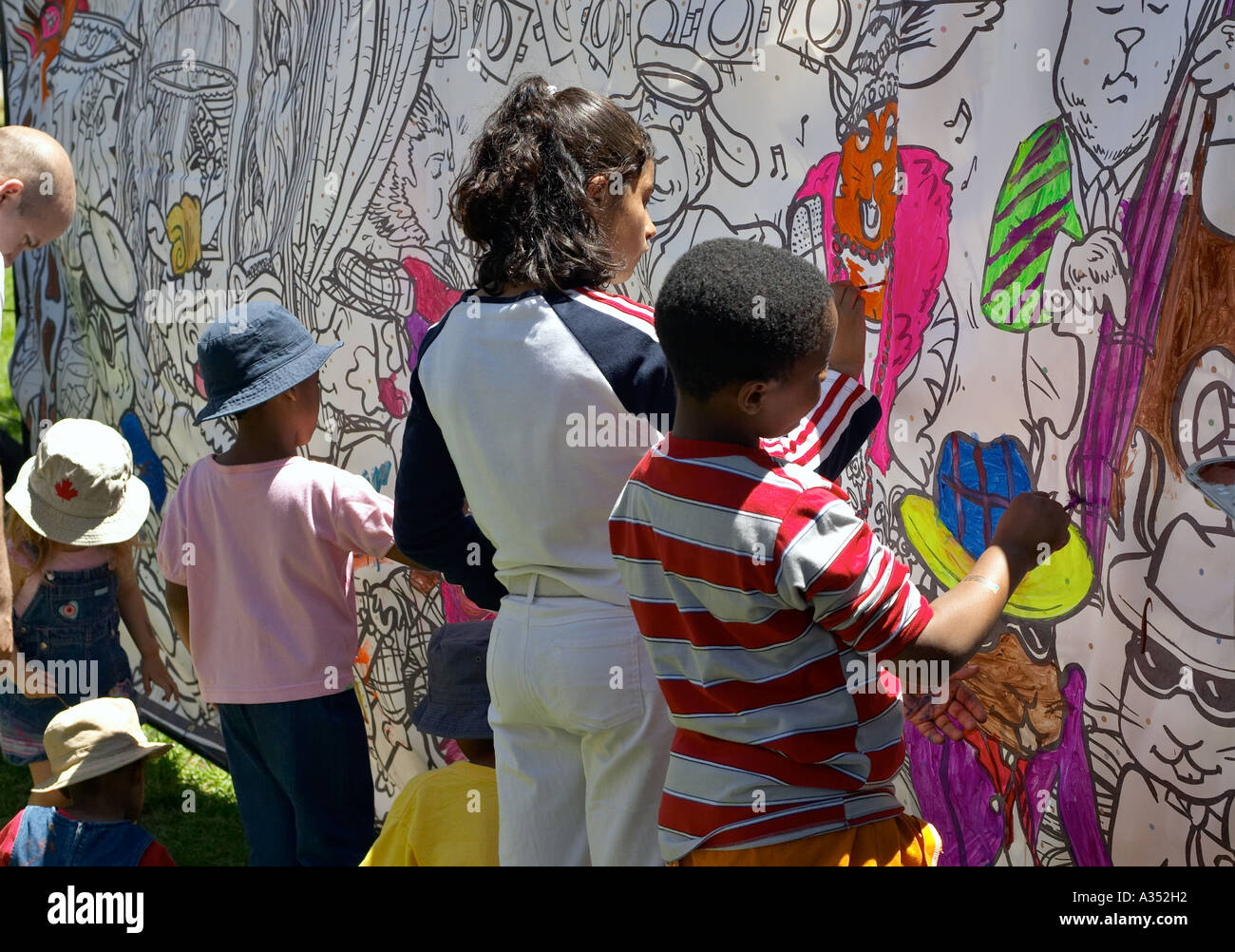 Hispanic, Arabic and African kids paint in a coloring mural. Outdoor summer activity. Toronto, Ontario, Canada. Stock Photo