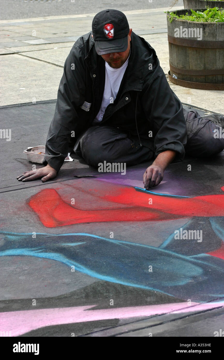 Street artist drawing Spiderman in chalk on the sidewalk. Stock Photo