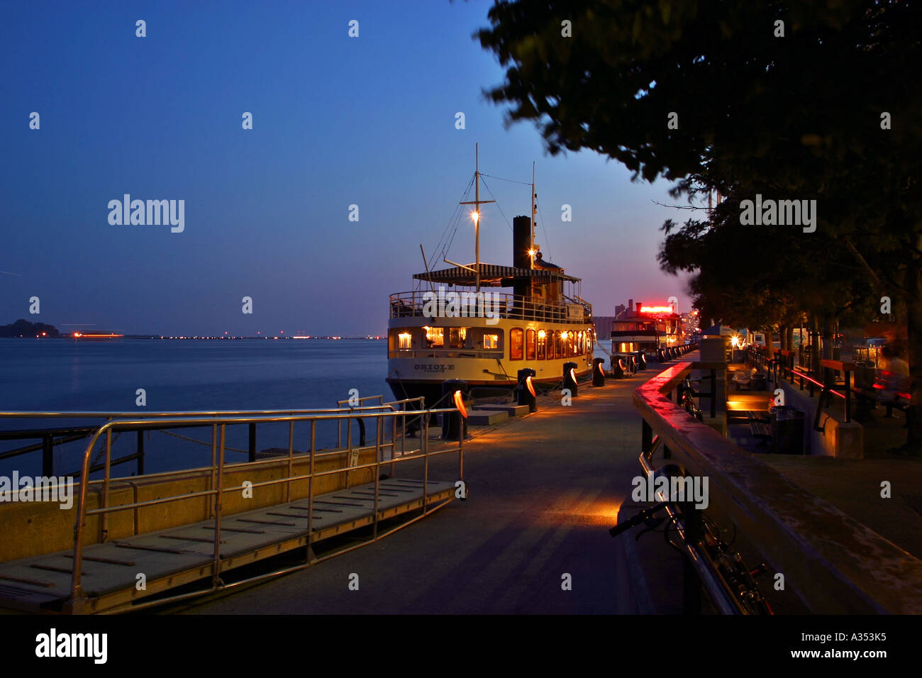 Toronto harbor at night. Boat-restaurant docked near the colorfully lit sidewalk. Stock Photo