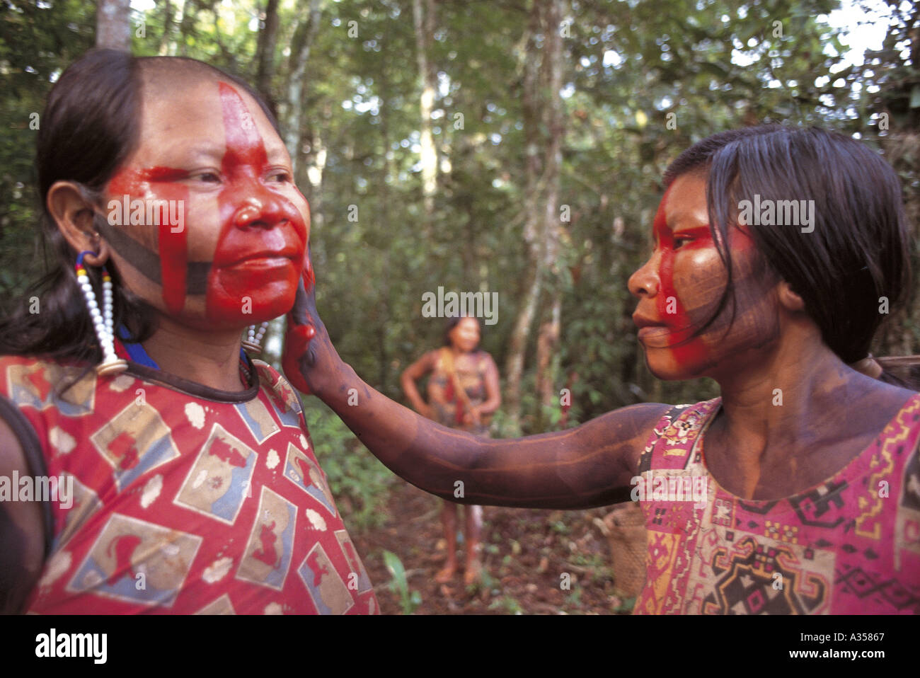 A Ukre Village Xingu Brazil Kayapo woman applying red Urucum Bixa orellana face paint it acts as an insect repellent Stock Photo