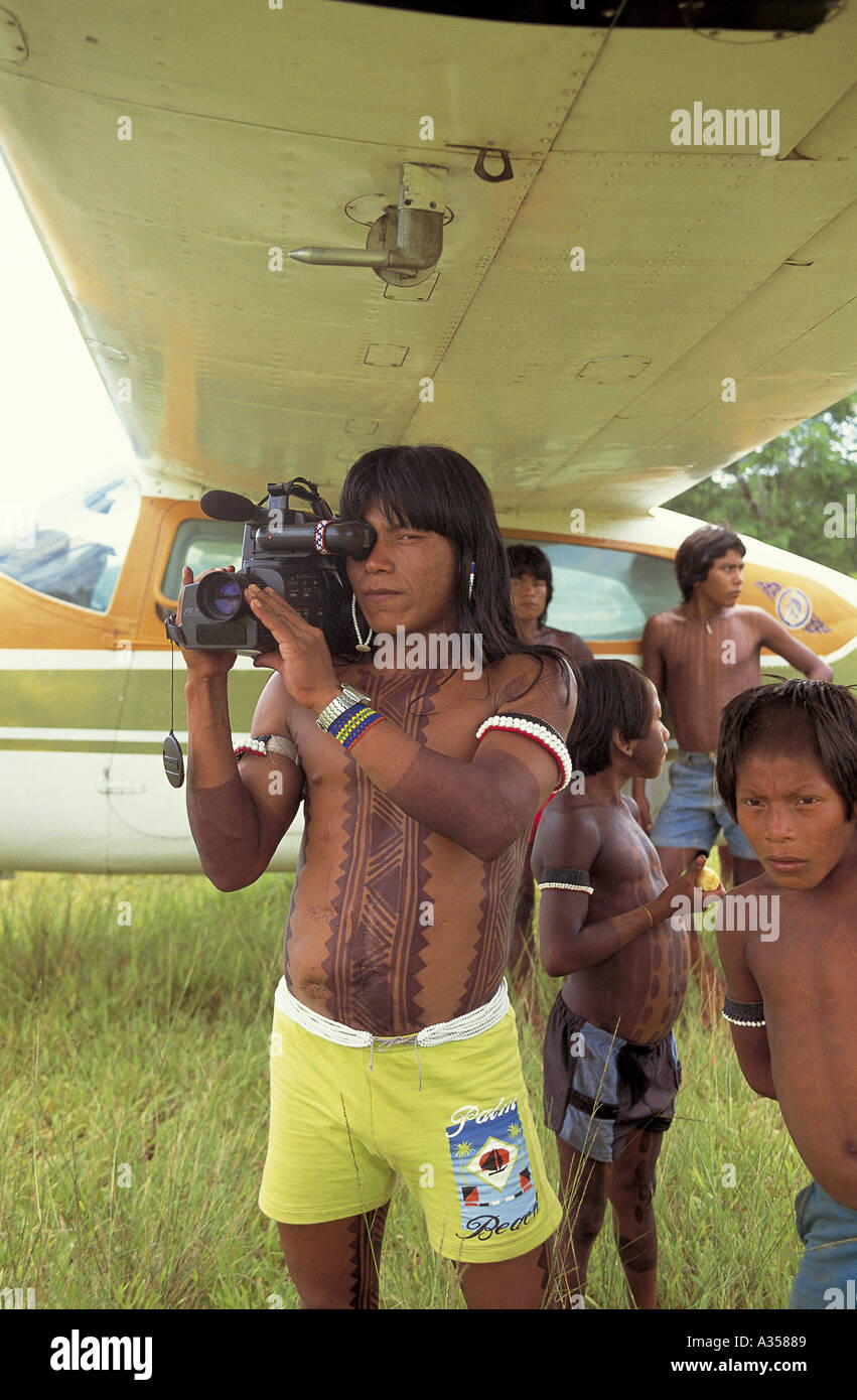 A Ukre Village Xingu Brazil Kin Abaiti a Kayapo man using a Panasonic video camera under the wing of an airplane Stock Photo