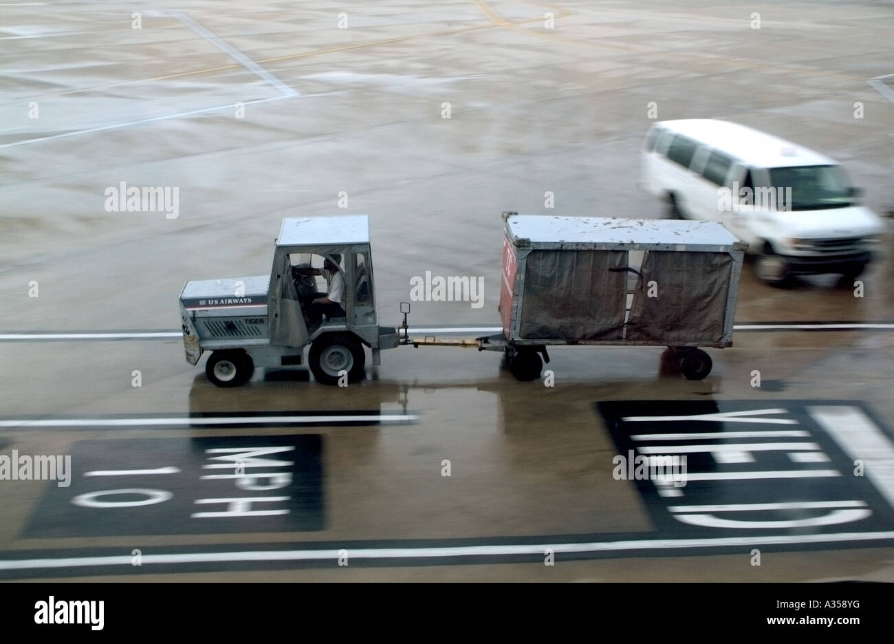 A baggage cart driving accross an airport runway Stock Photo Alamy