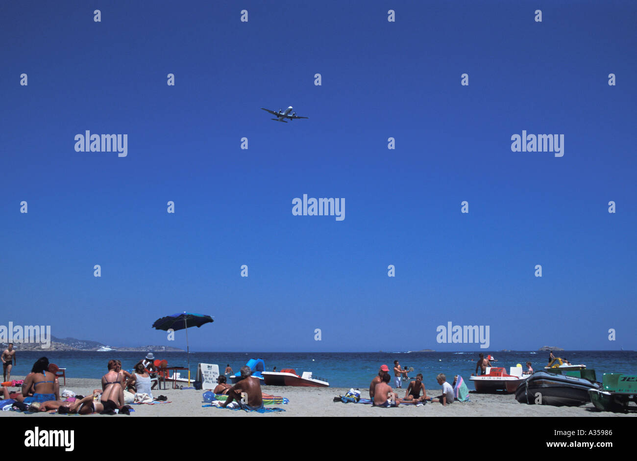 Plane flying over beach at Playa d'en Bossa Ibiza Spain Stock Photo