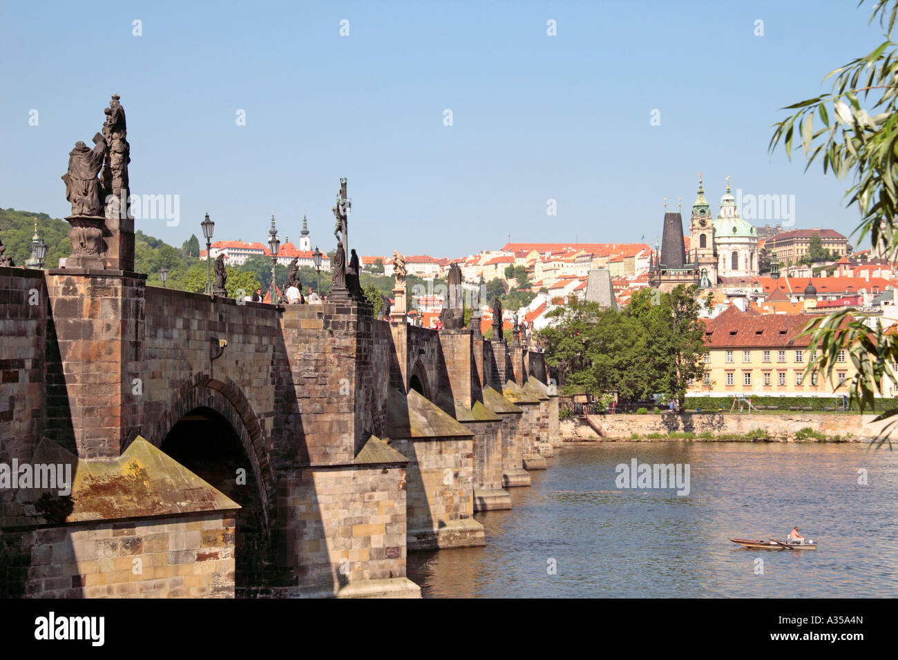 Charles Bridge over the Vltava river, Prague, with man fishing from boat in foreground Stock Photo