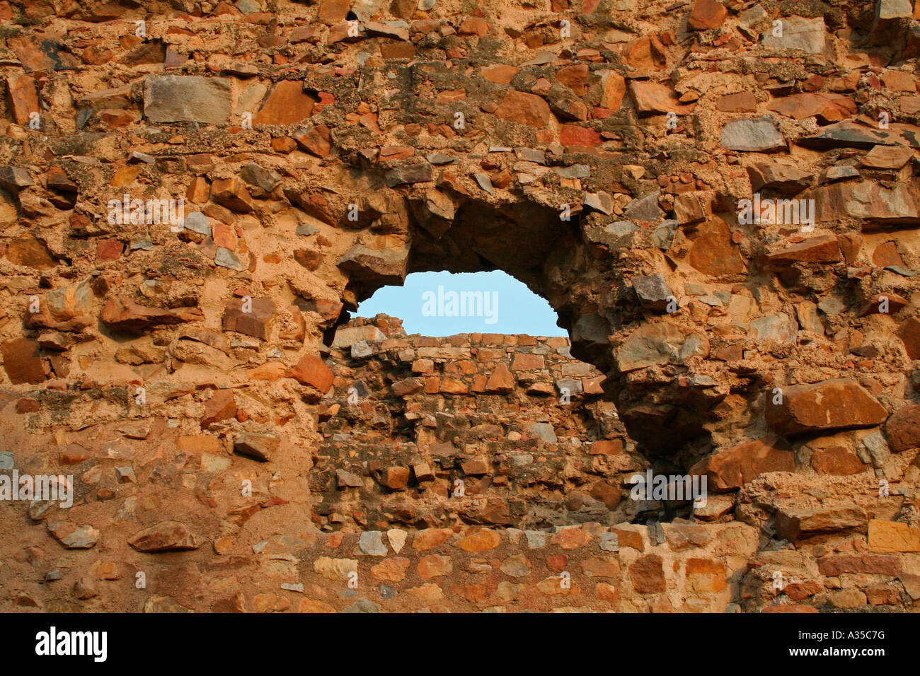 A wall and the sky above viewed through semi-circular window of an ancient ruined fort near New Delhi North India Stock Photo