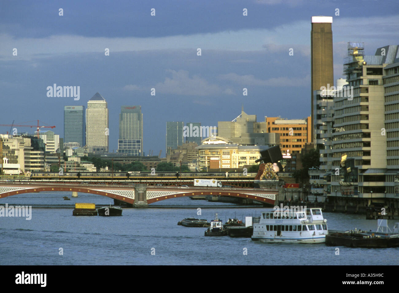 Looking east along the Thames River in London towards the Tate Modern and the towers of Canary Wharf in the distance Stock Photo