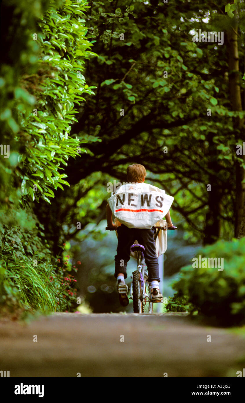 An 11 year old boy delivers newspapers in a leafy neighborhood Stock Photo