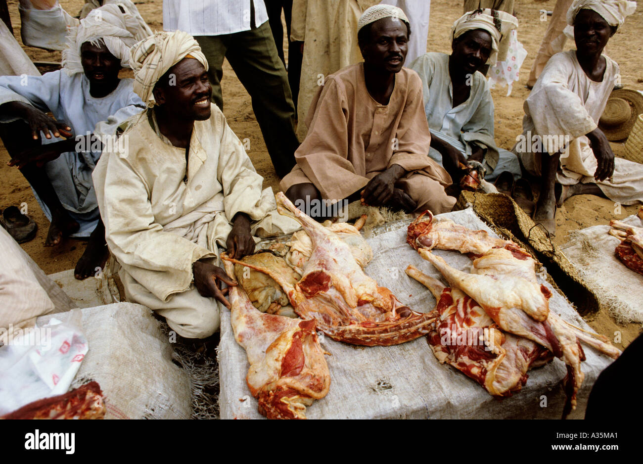 Sudan.Trading post of  El fasher in the Darfur region of western Sudan. Traders with their camels cut up meat for food. Stock Photo